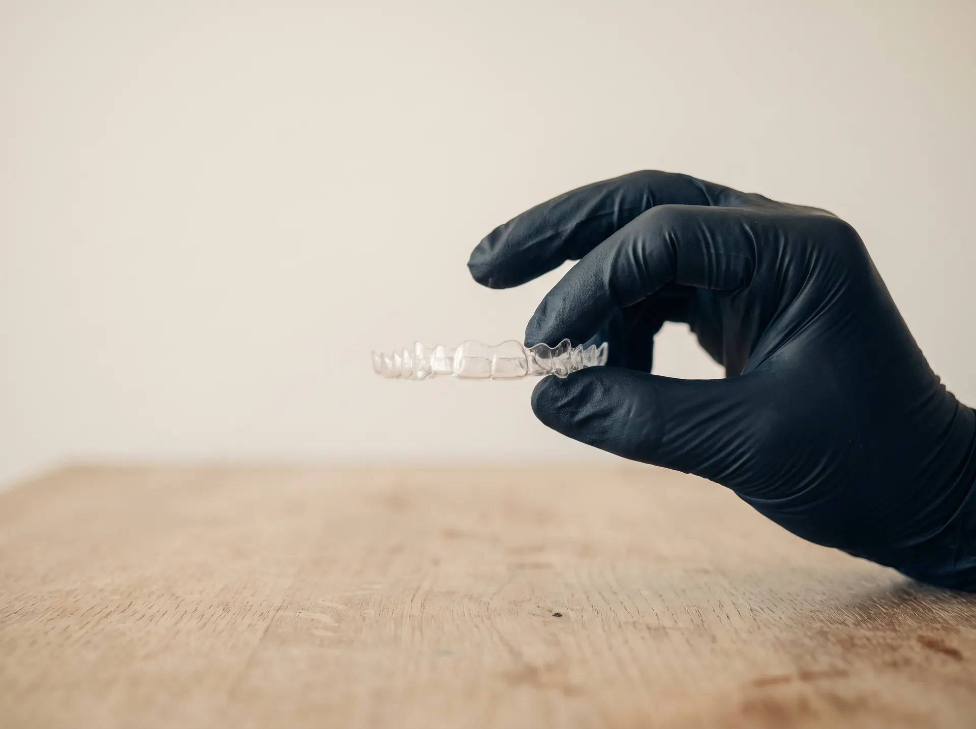 Aligneur transparent tenu par une main gantée au-dessus d'une table en chêne
